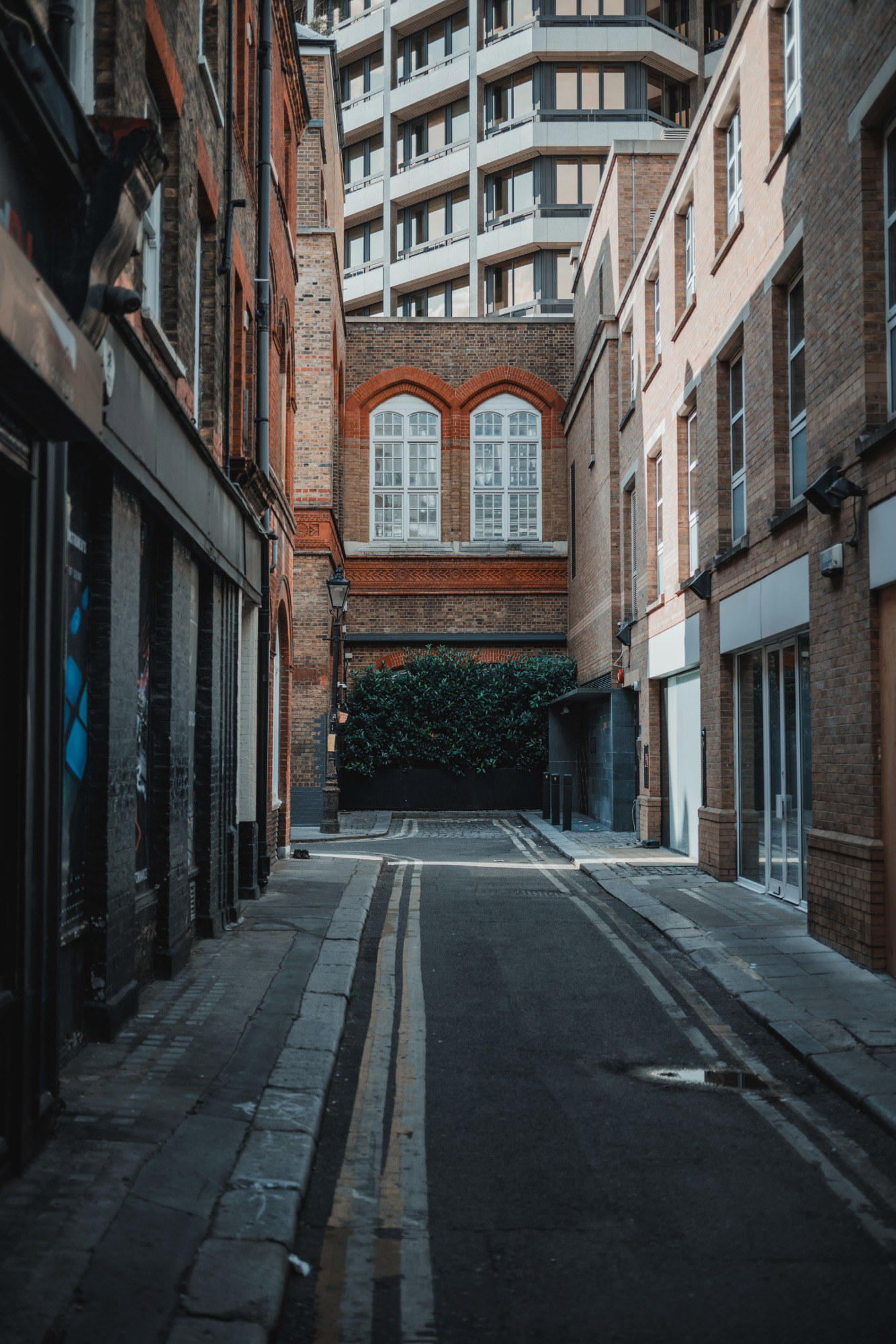 Een straatje in Londen waar de zon in valt. Achter de oude straat zien we een moderner flatgebouw.