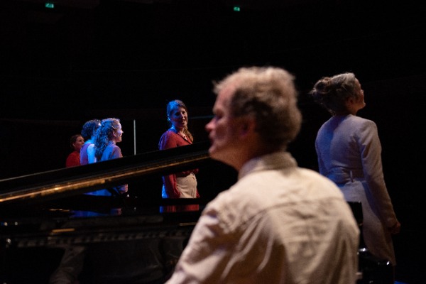 Bert van den Brink achter de piano met erachter Wishful Singing