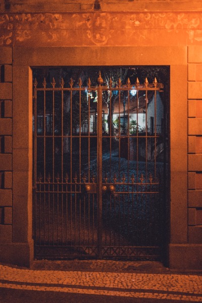 Een poort in de nacht, met daarachter een verlicht gebouw.