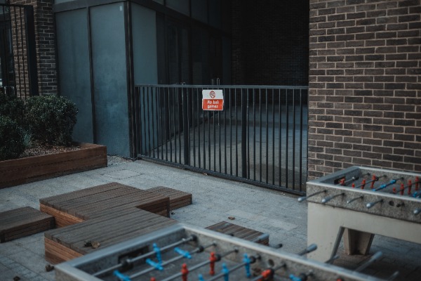 Een bordje 'No Ball Games' achter twee tafelvoetbaltafels.