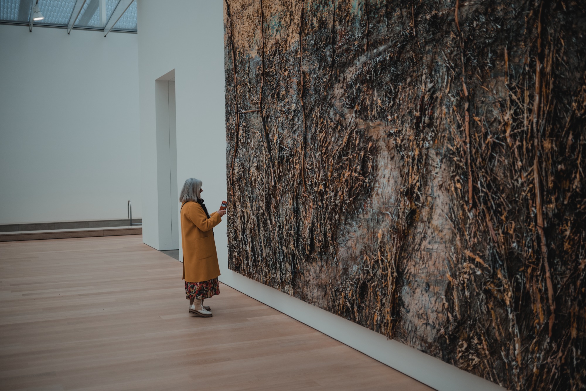 Een vrouw naast een grot schilderij van Anselm Kiefer in Museum Voorlinden