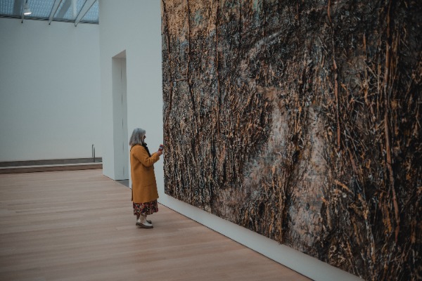Een vrouw naast een grot schilderij van Anselm Kiefer in Museum Voorlinden