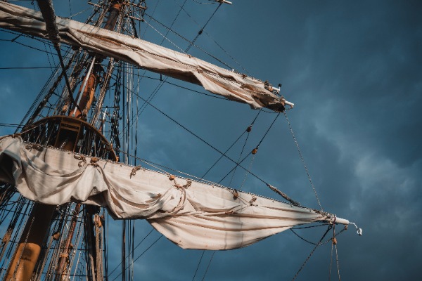 De mast van de Bark Europa in de zon, tegen een achtergrond van wolken