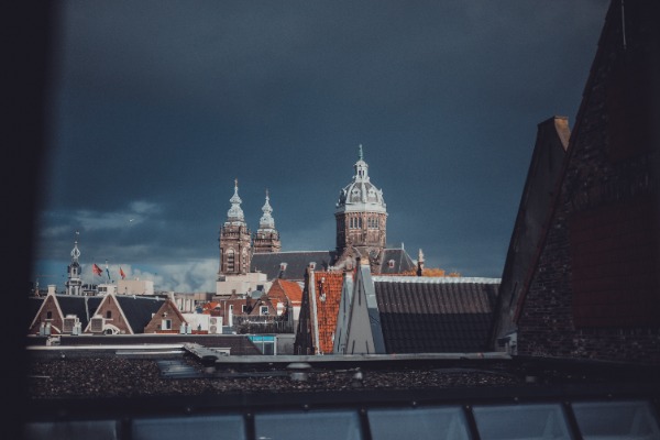 Uitzicht op de Oude Kerk met donkere wolken en zon.