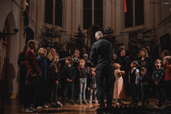 Dirigent met zangers en kinderen