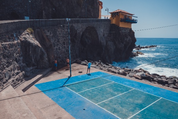 Een tennisveld aan het water, met erachter Ponta do Sol