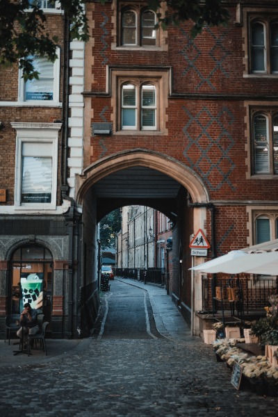 Een mooi steegje onder een gebouw door in Londen. Rechts staat een bloemenstal.