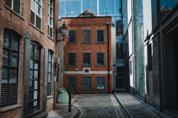 Een klein steegje in Londen. Achter oude gebouwen zien we een groot nieuw kantoorgebouw. In het straatje zien we een tent staan.