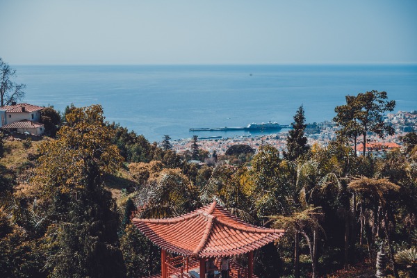 Een gebouw in Aziatische stijl en daarachter het park, nog verder Funchal en daarachter de zee