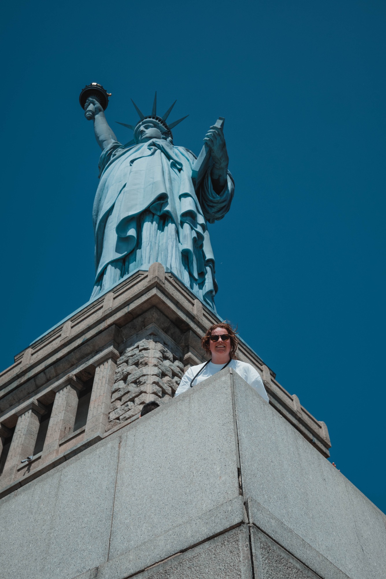 Een vrouw poseert aan de voet van het vrijheidsbeeld.
