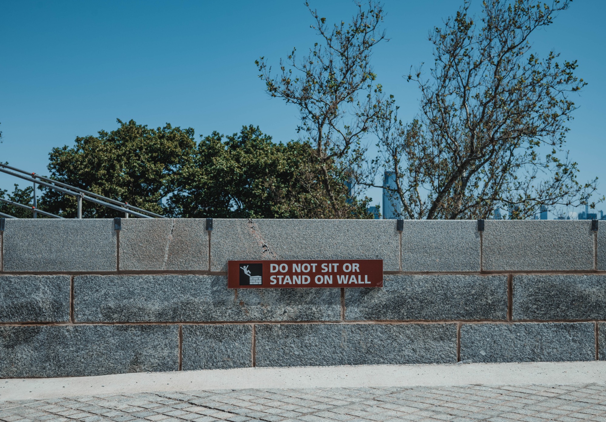 Een bordje 'Do not stand on wall' bij het vrijheidsbeeld.