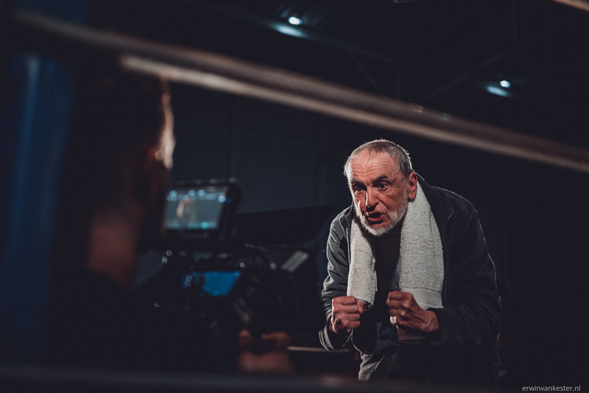 Trainer kijkt naar bokser, cameraman filmt