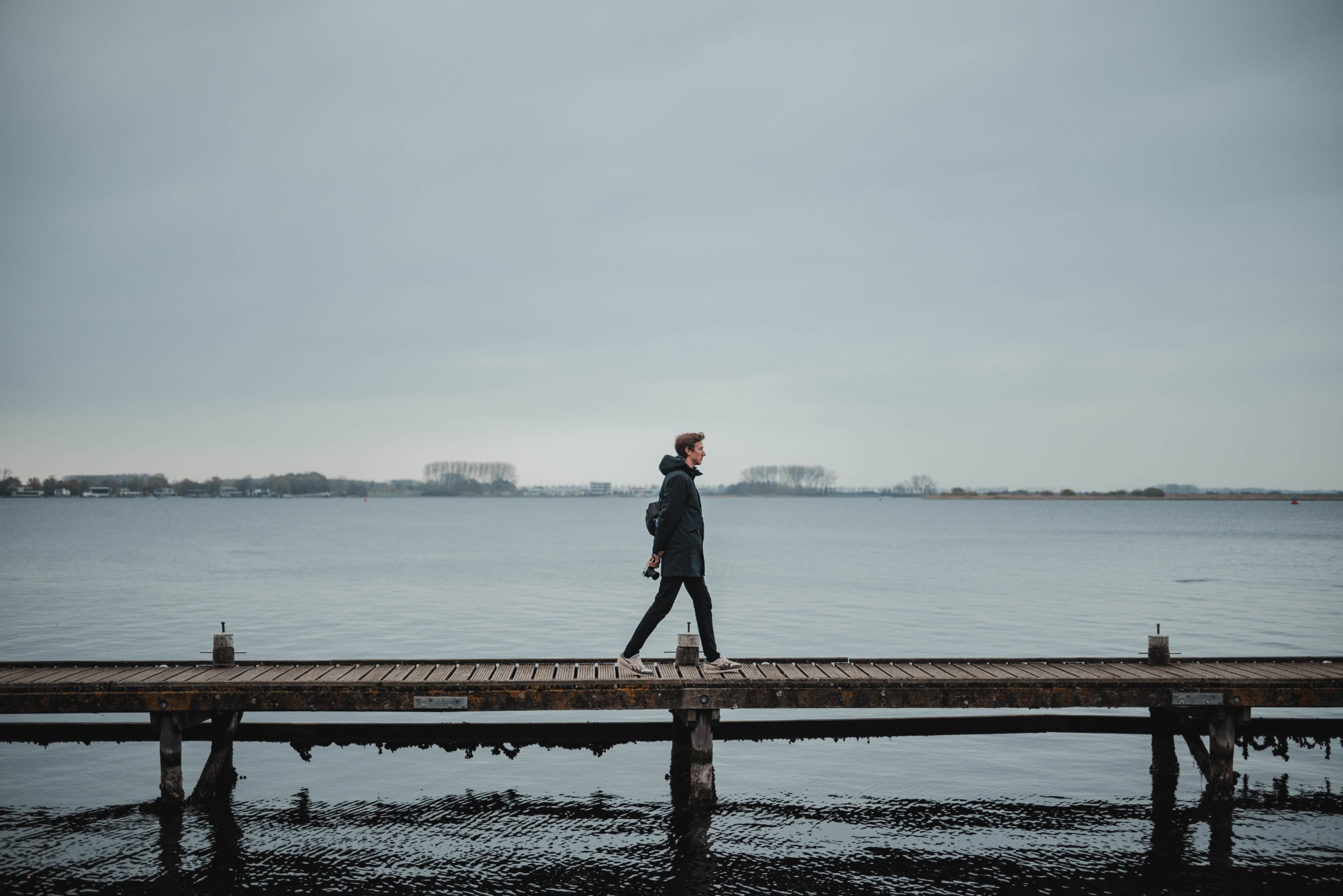 Tim loopt over een vlonder, achter hem het meer bij Veere