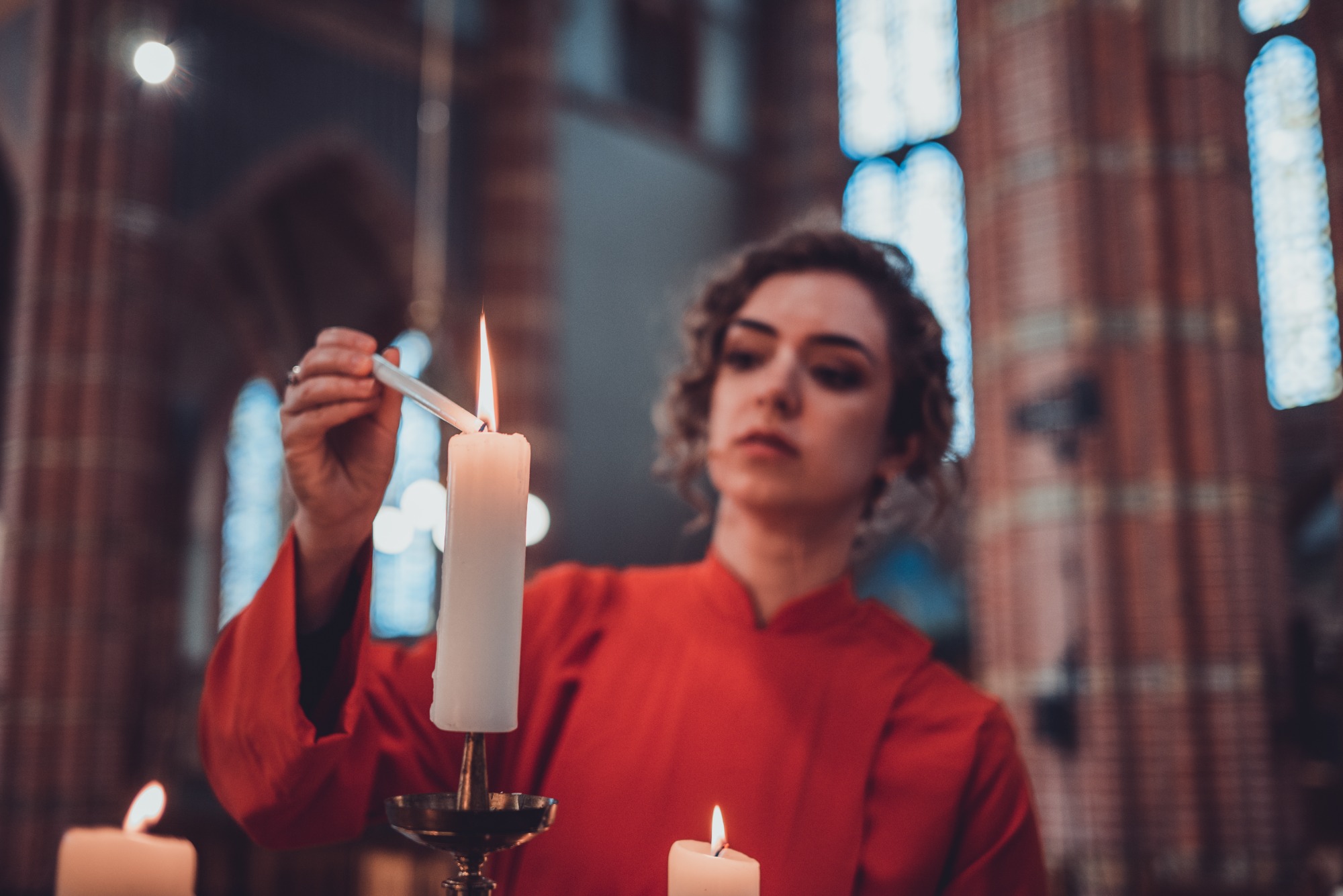 Zangeres van Wishful Singing steekt een kaars aan in de kerk.