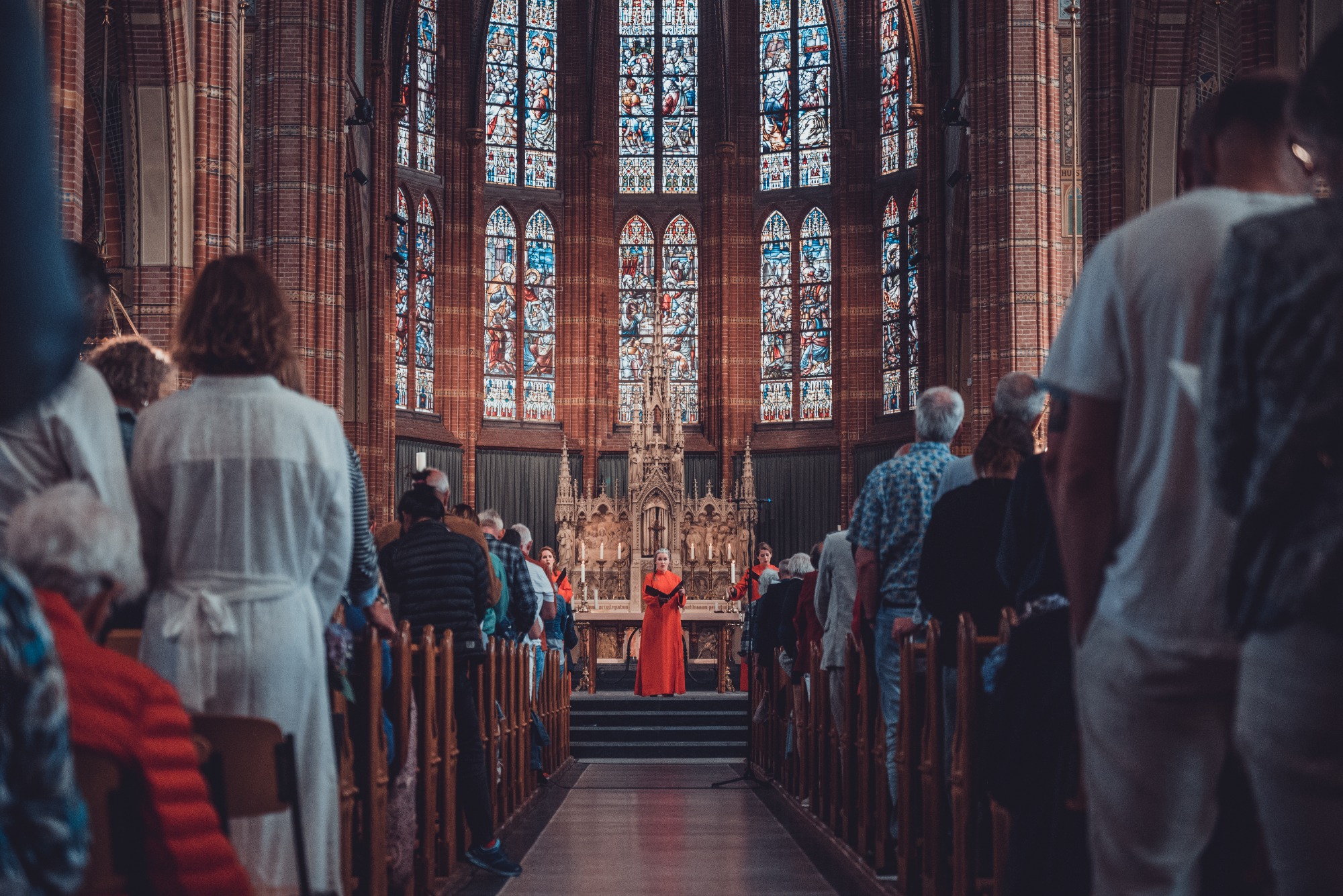 Een shot van achterin de kerk. We zien een zangeres van Wishful Singing tussen het publiek door.