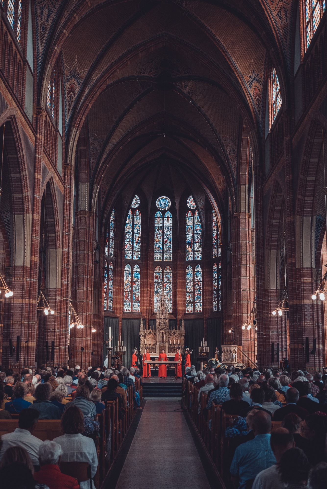 Een shot van achterin de kerk. We zien de zangeressen van Wishful Singing tussen het publiek door.