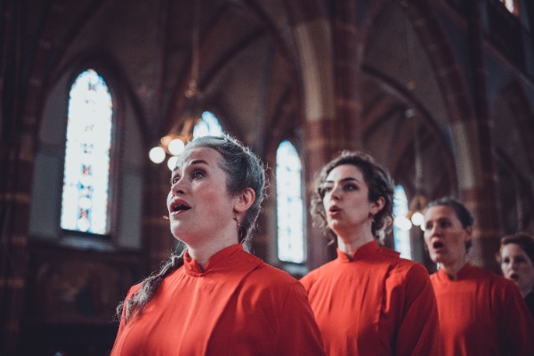 De zangeressen van Wishful Singing lopen in een rijtje naar voren in de kerk.